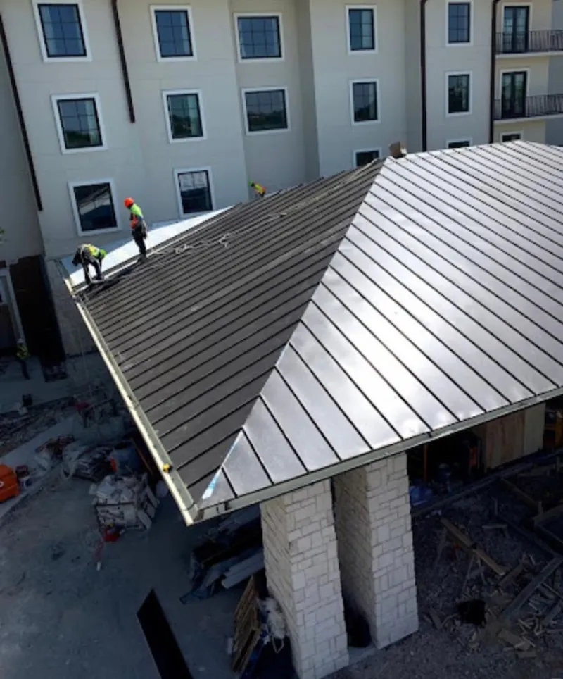 Crew installing standing seam metal roof panels on a commercial project in Lacey
